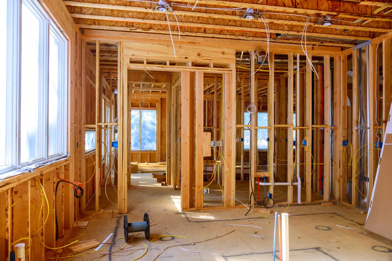 Worker installs electrical wires, insulation, and ceiling light before plasterboard in new house